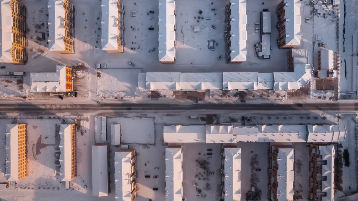 Overhead view of snow-covered urban buildings in winter, creating a geometric pattern.