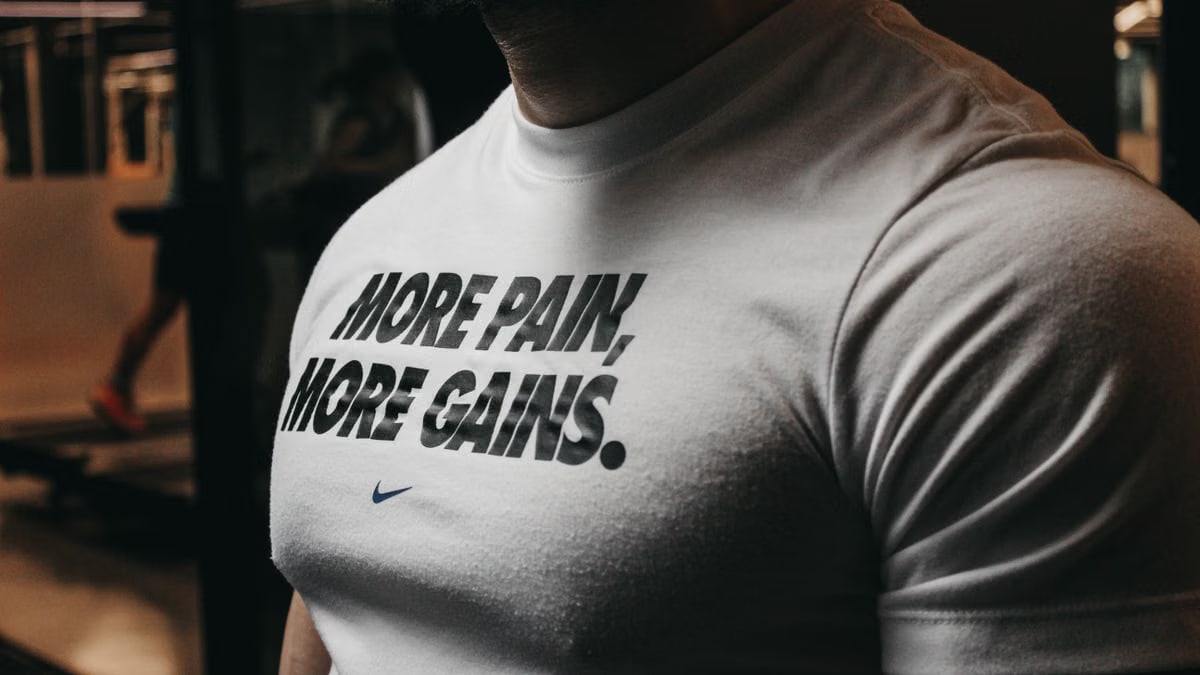 Close-up of a muscular man in the gym wearing a t-shirt with an inspiring fitness message.